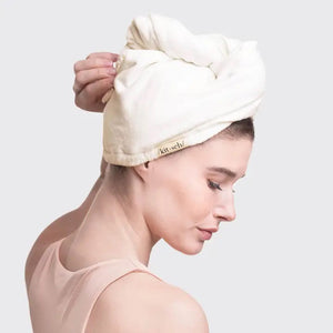 The KITSCH Quick Dry Hair Towel packaging highlights its luxurious eco-friendly blend of organic cotton and bamboo, showcasing softness and high absorbency. An image emphasizes friction-free drying, with the towel elegantly displayed beside the box, reflecting its natural allure.