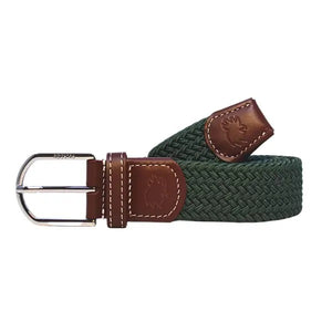 A person wears beige pants, a striped shirt with pink, green, and white lines, and the ROOSTAS - SIERRA WOVEN STRETCH BELT by ROOSTAS—a dark green braided belt with brown leather accents and an adjustable clasp.