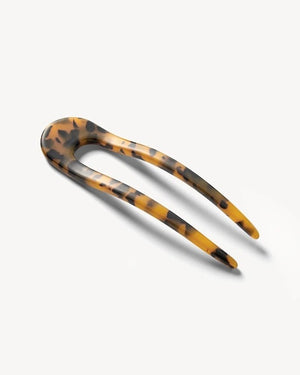 A smooth, black MACHETE - FRENCH HAIR PIN with two prongs, crafted from Italian acetate by MACHETE, rests on a plain white surface.