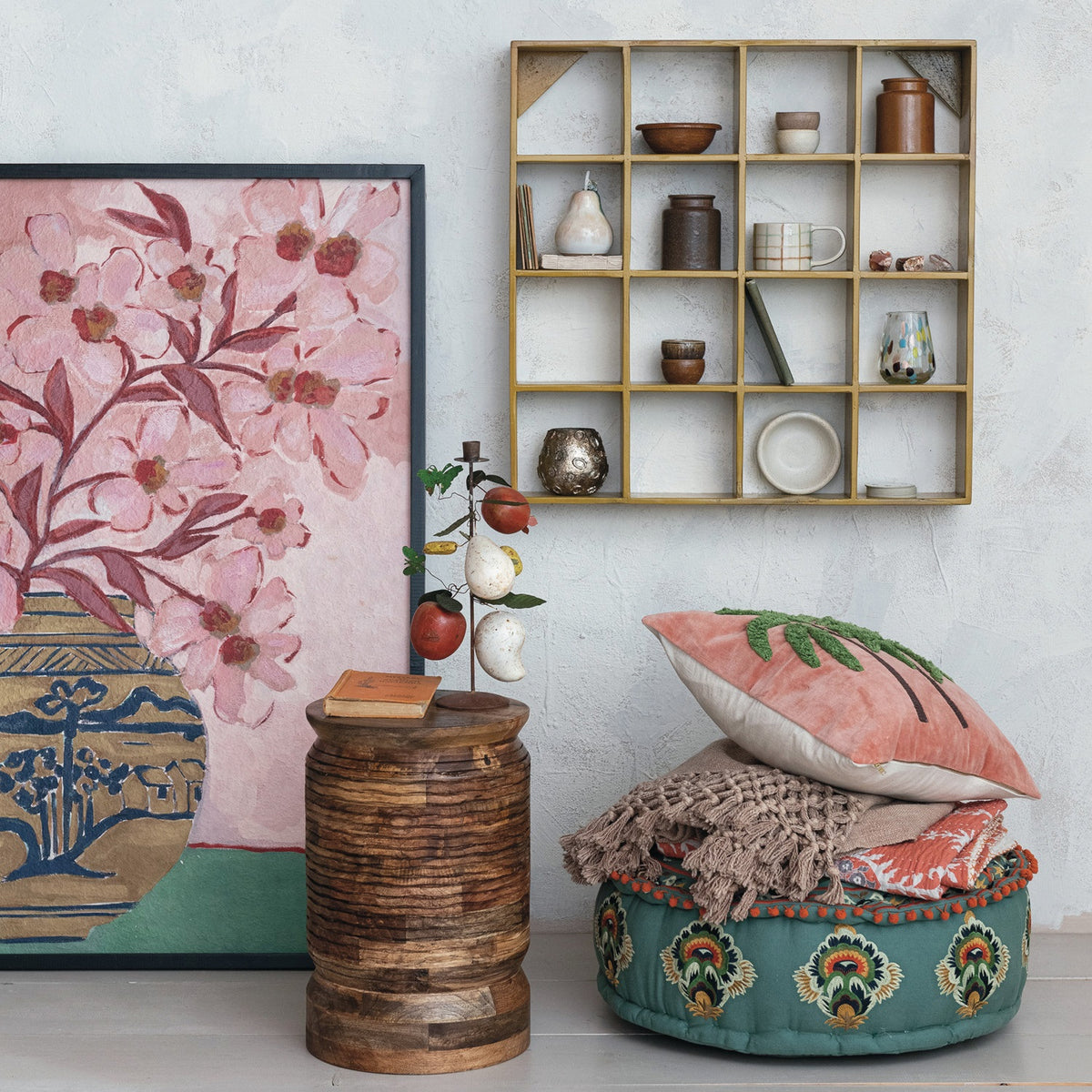 Introducing the WOOD FRAMED FLORAL WALL ART - PINK FLOWERS IN CHINOISERIE VASE from CREATIVE COOP. This oversized wall decor showcases a painting of pink flowers with red stems arranged in a decorative chinoiserie vase adorned with an intricate landscape pattern of trees, hills, and water. Set against a background that transitions from light pink above to green below, this elegant piece is beautifully framed in black wood, making it a striking addition to any space.