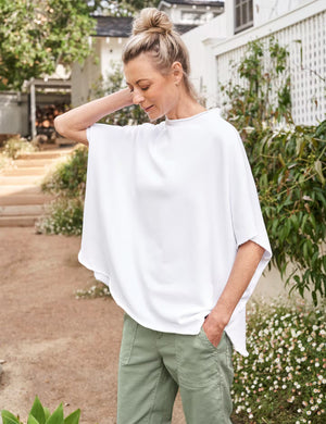 The FRANK & EILEEN Olive Original Capelet in white, a 100% cotton T-shirt with short sleeves and a wide neckline, hangs against a textured light gray background.