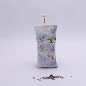 The L'AUGUSTE PROVENCE - FRENCH LAVENDER SACHET FROM PROVENCE features a painted house in a lavender field, stands upright with dried lavender in front, and is topped with a white "L'AUGUSTE" ribbon—authentic from Provence.