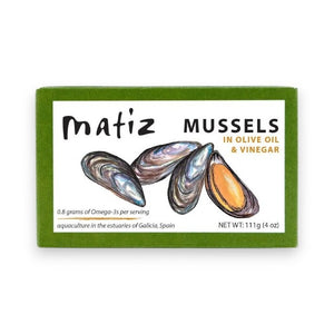 A green box of MATIZ ESPANA - MATIZ Mussels in Extra Virgin Olive Oil highlights its omega-3 content and origin from Galicia, Spain, with illustrations of Spanish mussels. Net weight: 111g.