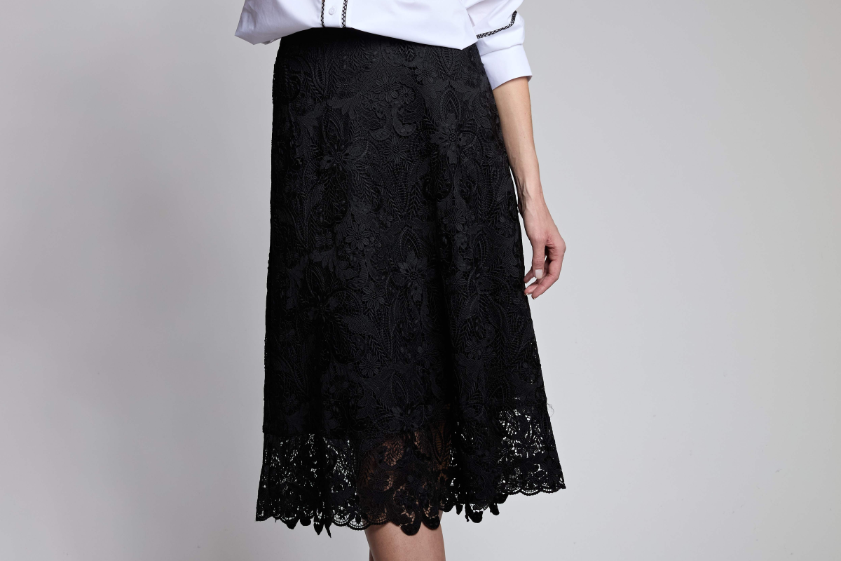 Black lace skirt worn by a person on a gray background