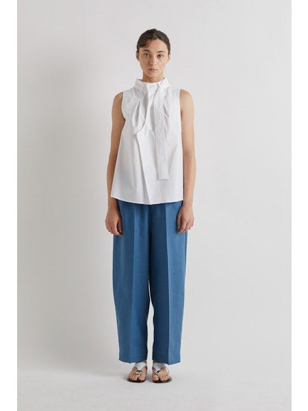 A person stands against a plain light background, cropped at the shoulders, wearing MEIMEIJ Pull On Barrel Pant in Cerulean with an elastic waistband, paired with a white shirt and sandals.