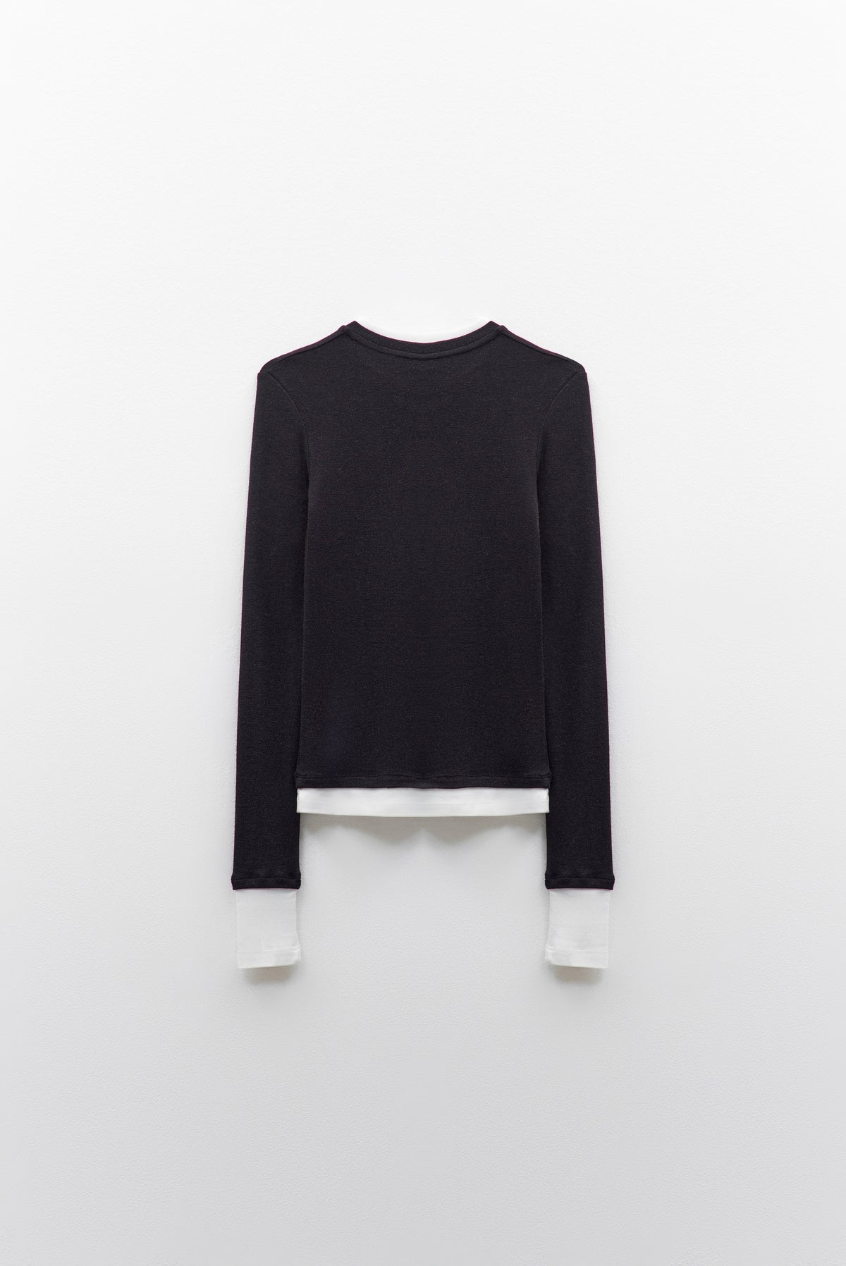 The ELEH - THE CONTRAST LAYER TOP by ELEH is a modern black long-sleeved sweater with white trim on the collar, cuffs, and hem—an effortlessly versatile wardrobe essential shown flat against a white background.