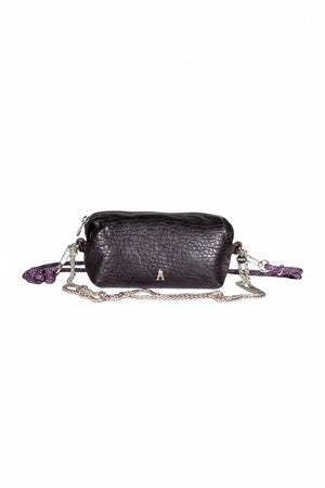 The CRAIE STUDIO - NUAGE BUBBLE POURPRE MINI BAG, a compact and textured black lambskin accessory featuring silver hardware and an eye-catching purple patterned strap, is showcased on a white pedestal against a plain background.