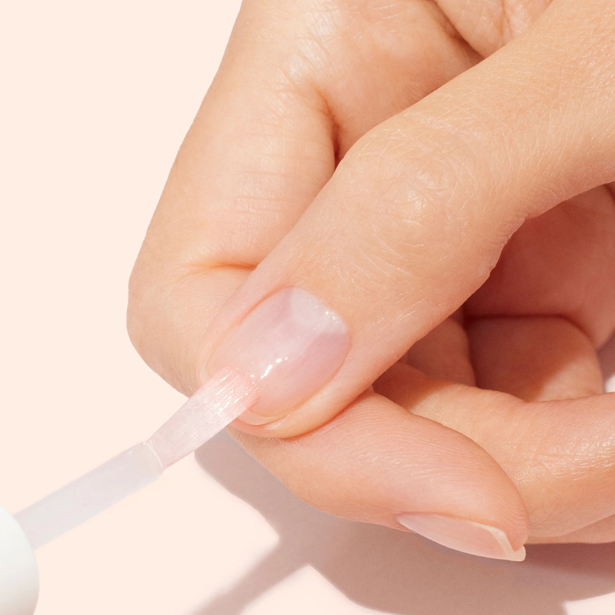 A clear glass bottle of MANUCURIST INC MANICURIST - S.O.S. NAIL MASK featuring pink liquid, a white cap, and a green label. This hydrating night care formula is designed to repair and restore damaged nails.