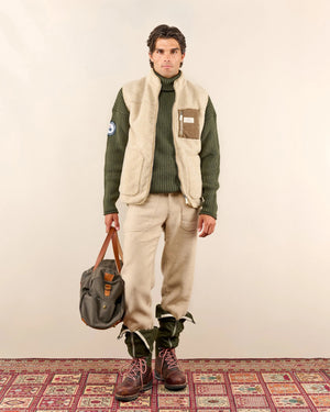 AMUNDSEN SPORTS - HEROES FLEECE VEST NATURAL by AMUNDSEN SPORTS is a beige sherpa wool fleece vest with a high collar, front zipper, two side pockets, and a waxed cotton chest pocket detailed with a small label. Made in Portugal, the vest is displayed laid flat on a white background.
