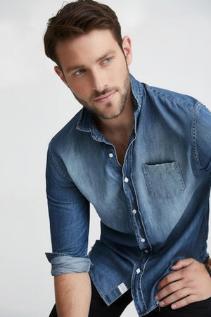 The FRANK & EILEEN LUKE Men’s Famous Denim Distressed Vintage Wash button-up features long sleeves, a front pocket, rolled cuffs, relaxed fit, visible collar label, and comes in light blue Italian denim against a white background.
