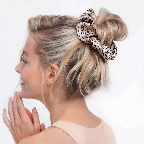 A leopard print KITSCH - ECO FRIENDLY BRUNCH SCRUNCHIE, made from recycled fabric, rests on a light gray background. The satin-finish label reads "kit•sch" in lowercase.