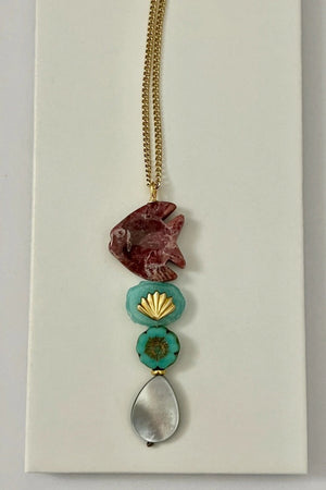 The SANDRINE FRANCE STUDIO - COMPANION LEO NECKLACE features a rhodonite fish pendant, two green Peruvian aventurine beads, and a teardrop-shaped gray stone on a gold chain—an elegant handmade piece from SANDRINE FRANCE STUDIO.