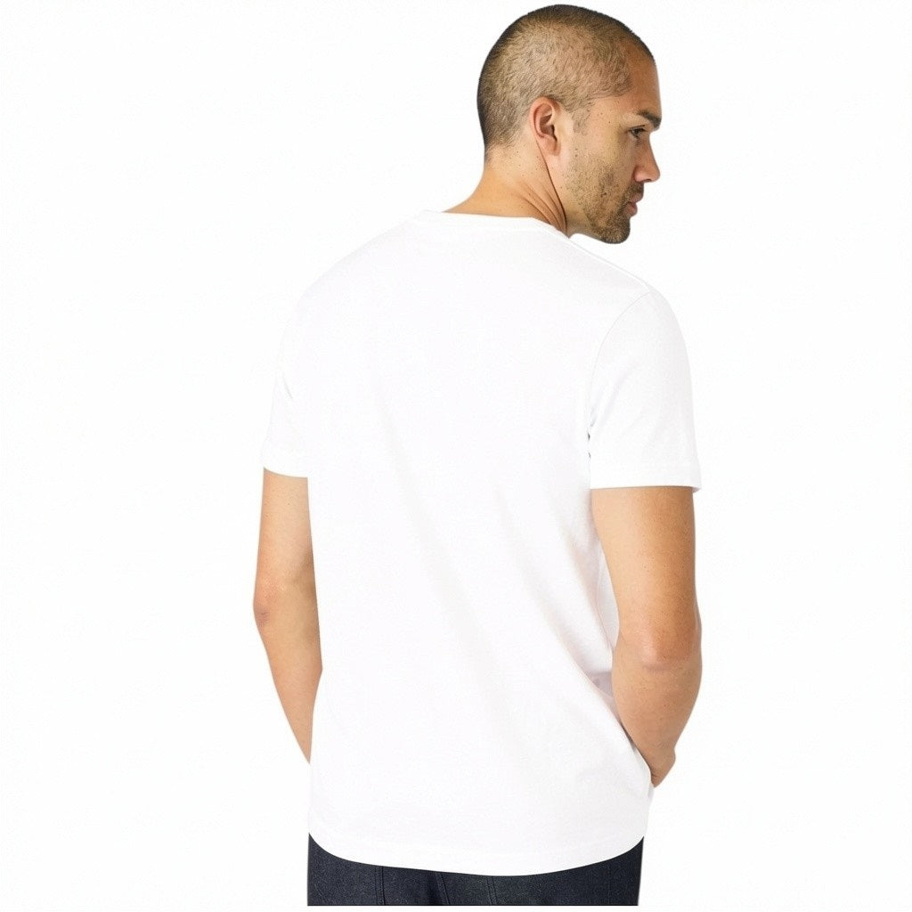A man with short hair and light stubble wears the MACK WELDON Slub Cotton Crew Neck T-Shirt in Bright White, paired with dark pants, standing against a white background and looking slightly to his left.