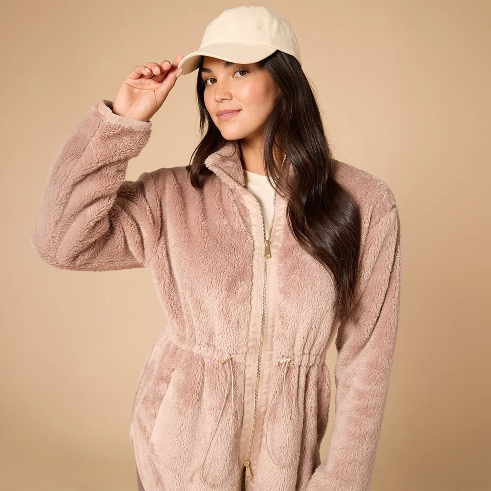 A woman wearing a cream SOFTIES - DREAMPLUSH DOUBLE ZIP JACKET / TUNIC with a cinched waist, paired with wide-leg denim culottes for cozy velvety softness.