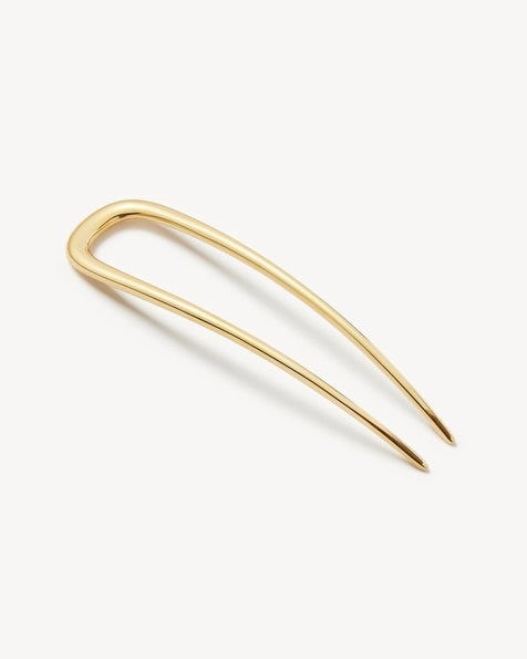 The MACHETE - MIDI FRENCH HAIR PIN IN GOLD by MACHETE is a handcrafted, U-shaped hair accessory with two long, pointed prongs, standing vertically against a plain white background to highlight its elegant simplicity.
