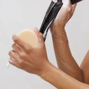 A round, beige solid conditioner bar sits on its light gray packaging labeled "KITSCH Coconut Repair Deep Conditioning Bar Mask." Infused with coconut oil for softness and shine, it detangles and conditions. The package highlights "Color Safe," "pH Balanced," "Vegan," and plastic reduction.