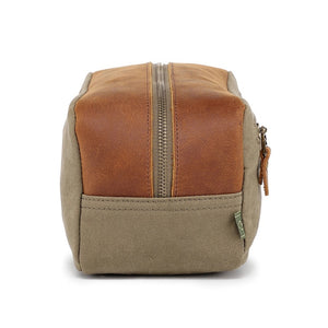 The TSD BRAND Valley Oak Toiletry Bag in olive is a rectangular, handcrafted travel essential made from durable canvas, featuring a tan leather strap and a small leather patch for added style.