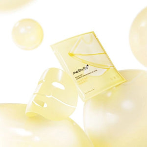 A woman wears the MEDICUBE - KOJIC ACID TURMERIC BRIGHTENING GEL MASK by KOSMIC KBEAUTY SKINCARE on one half of her face in its original gold jelly form, while the other half reveals the mask after it has turned transparent. Text highlights this Korean skincare treatment, infused with kojic acid and turmeric, which absorbs over 3-4 hours and transforms from gold to clear for a radiant, brightening effect.