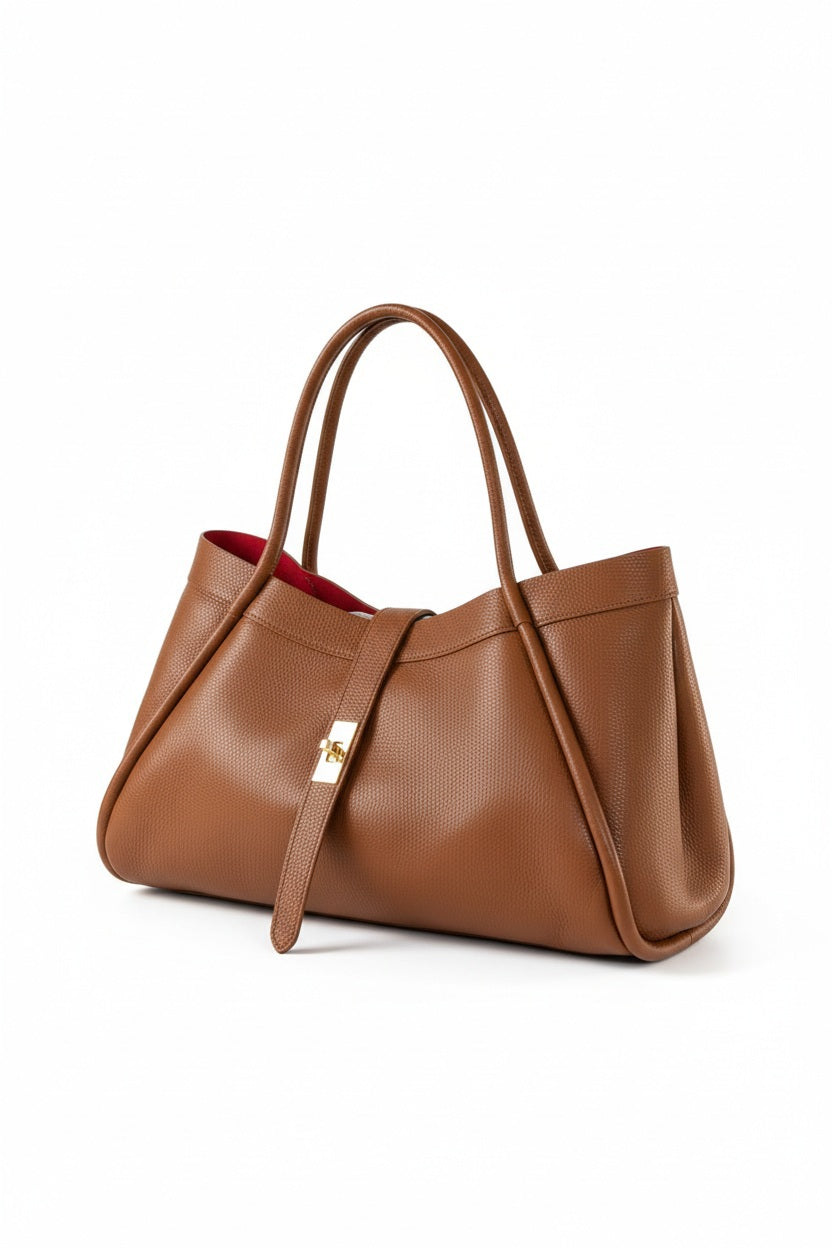THE PORTICO LEATHER HANDBAG IN COGNAC, a tan suede leather handbag with a central gold-tone turn-lock closure and a bright red interior.