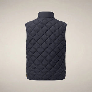 A person stands facing forward, wearing the SAVE THE DUCK - FABRICE Puffer Vest in Blue Black from SAVE THE DUCK, featuring recycled Plumtech insulation, layered over a black long-sleeve shirt and gray pants. They have a neutral facial expression and are posed against a plain white background.