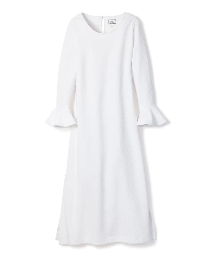A long-sleeved white PETITE PLUME - LUXE PIMA NIGHTGOWN, crafted from Peruvian Pima cotton, hangs against a white background. The nightgown features a round neckline and flared sleeves with ruffled cuffs. With a subtle quilted effect and simple, elegant design, it exudes the charm of luxurious sleepwear.
