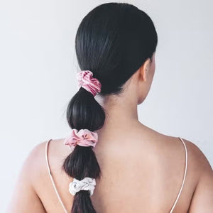 The KITSCH Velvet Scrunchies, perfect hair accessories in dusty pink and sage green, boast a soft texture. They come elegantly gathered on a white card labeled "KITSCH" with "SCRUNCHIE" below.