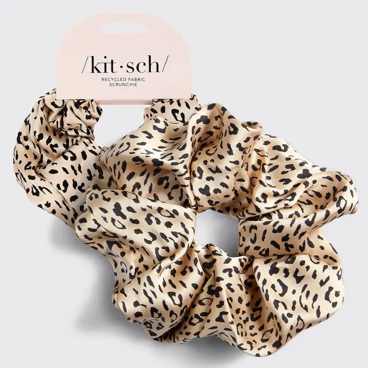 A leopard print KITSCH - ECO FRIENDLY BRUNCH SCRUNCHIE, made from recycled fabric, rests on a light gray background. The satin-finish label reads "kit•sch" in lowercase.