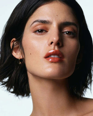 A light gray tube labeled "U BEAUTY - THE PLASMA LIP COMPOUND 15ML" with a screw cap stands upright on a white background, offering advanced hydration and plumping for lips. Brand: U BEAUTY.