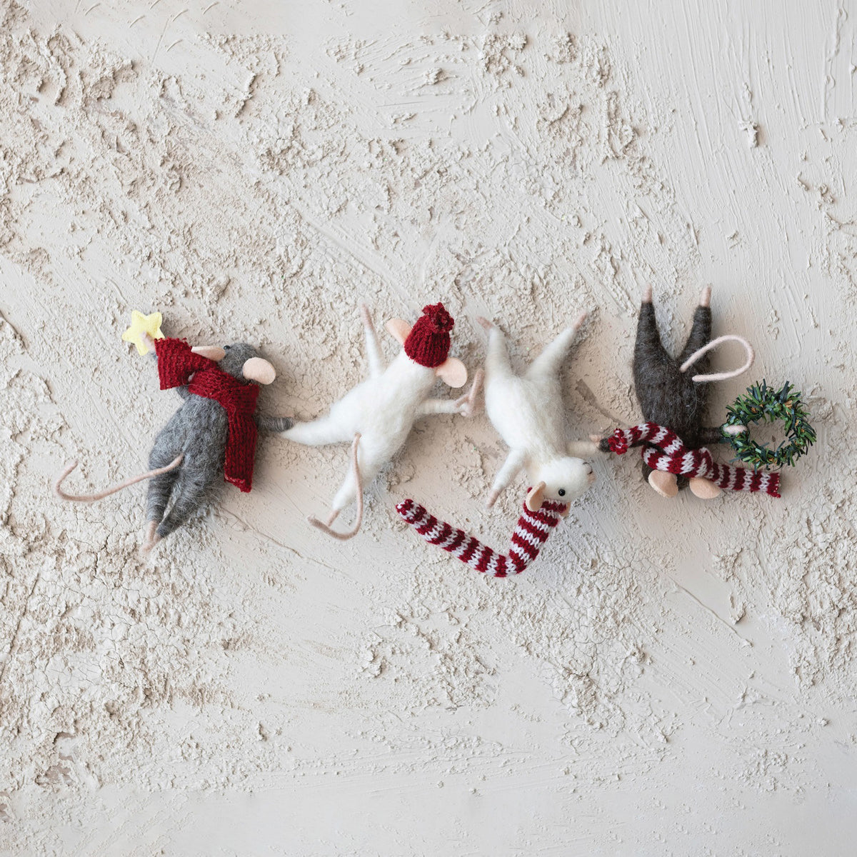 The CREATIVE COOP FELT MICE HANGING FROM WREATH features four playful felt mice dressed in winter hats and scarves, each hanging vertically, with one mouse holding a tiny wreath and another holding a star.