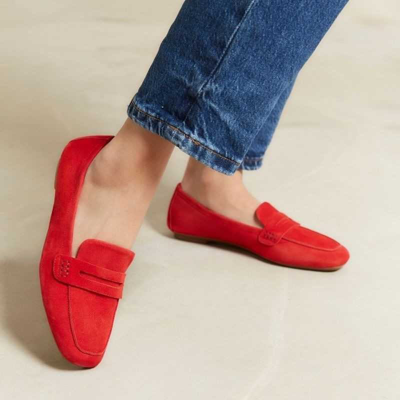 The REQINS HEMA Suede Loafer in Rouge features bright red suede, low heels, a classic penny loafer design, and a supple leather insole—all crafted with artisanal expertise and shown on a plain light background.