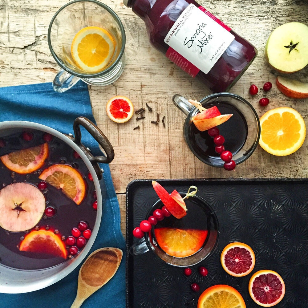 A glass bottle of STONEWALL KITCHEN - SANGRIA MIXER from STONEWALL KITCHEN features a maroon liquid, is labeled as gluten free and non-GMO, and has a metal cap with a cream-colored label displaying product details. Ideal for making fruity drinks or party cocktails.