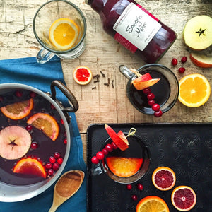 A glass bottle of STONEWALL KITCHEN - SANGRIA MIXER from STONEWALL KITCHEN features a maroon liquid, is labeled as gluten free and non-GMO, and has a metal cap with a cream-colored label displaying product details. Ideal for making fruity drinks or party cocktails.