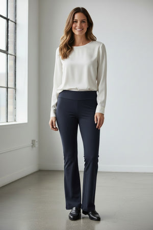 A person is showcased against a white background wearing KRAZY LARRY, INC's MICROFIBER PULL ON PANT - LONG in a high-waisted design paired with sleek black heeled sandals. Their top and arms are partially visible, contributing to an elegant silhouette.