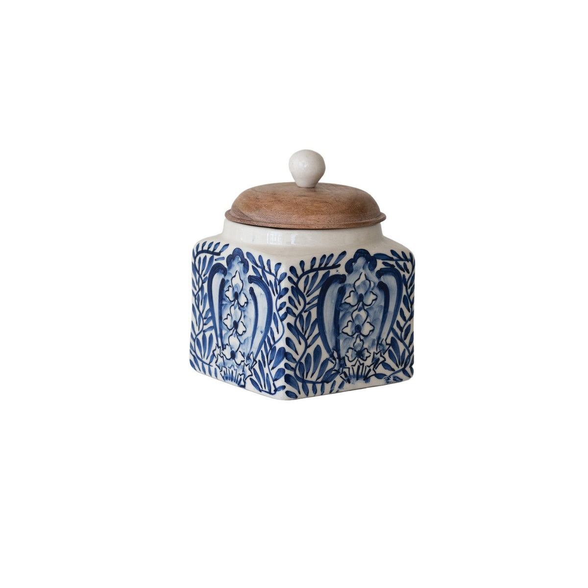 A close-up of the CREATIVE COOP HAND-PAINTED STONEWARE CANISTER WITH LID AND SPOON shows blue floral designs on cream stoneware and an acacia wood lid—an elegant farmhouse kitchen accent.
