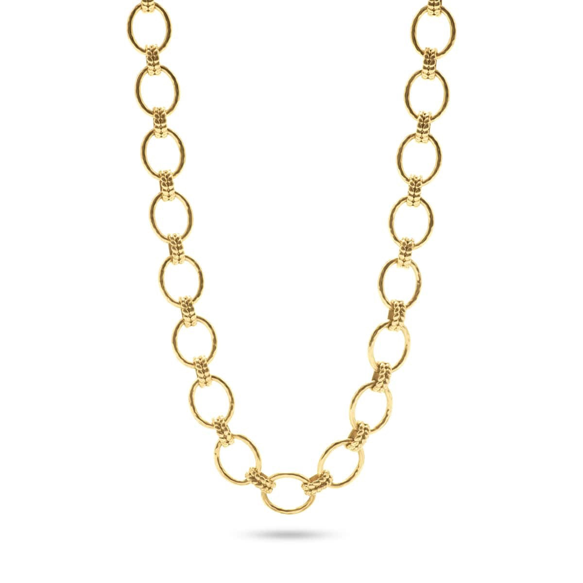 A person in a white blouse displays the CAPUCINE DE WULF - CLEOPATRA GRANDE LINK NECKLACE, made of 18K gold with circular links. Their hands feature gold rings, emphasizing the handmade jewelry's elegance.