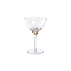 Introducing the MARTINI COCKTAIL OPTIC GLASS by ZODAX: a clear, elegant stemmed glass featuring a shallow, wide bowl. The glass boasts a detailed, decorative stem and a circular base. With a 150 ml capacity, its minimalist and sophisticated design is ideal for serving champagne or cocktails.