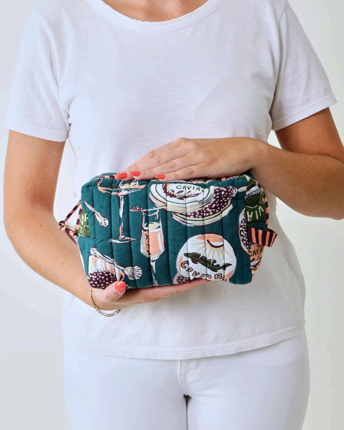 Adorned with an illustrated pattern of caviar tins, open shells brimming with caviar, delicate spoons, and tall champagne glasses on a rich peacock feather green background, the PRINTFRESH - CHAMPAGNE & CAVIAR QUILTED POUCH IN PEACOCK FEATHER is an elegant accessory from PRINTFRESH. This stylish pouch makes a perfect gift for her.