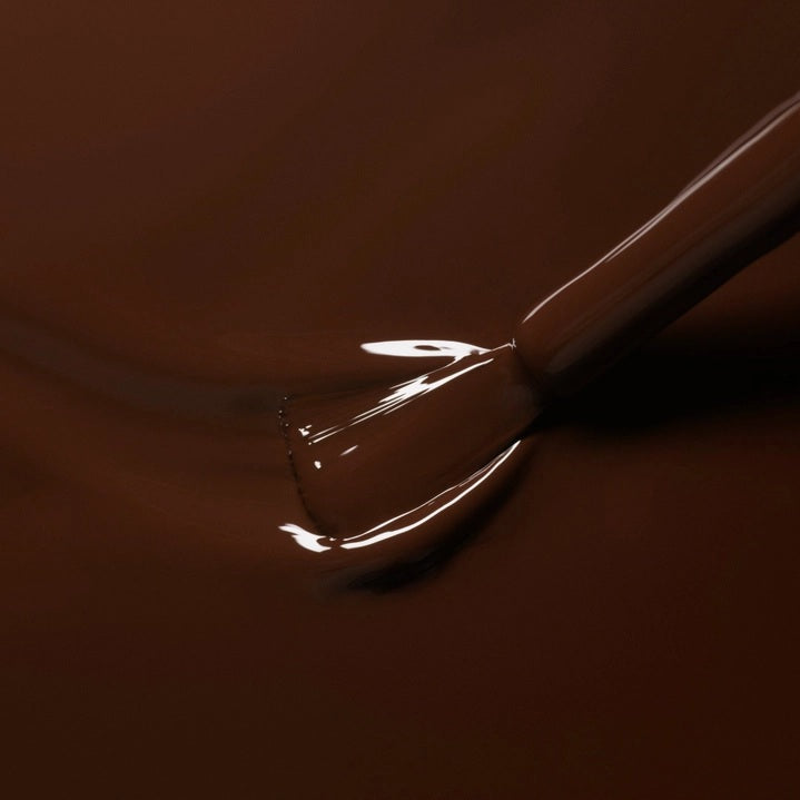 A bottle of MANUCURIST - GREEN™ Nail Polish in Clove by MANUCURIST INC, featuring a rich chocolate brown shade and a black cap. The label reads “green quick dry intense color.”.