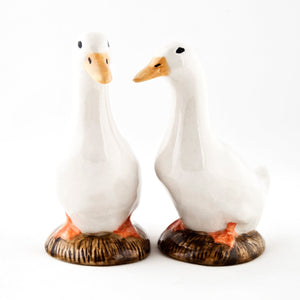 The QUAIL CERAMICS - PEKIN DUCK SALT AND PEPPER SET by QUAIL DESIGNS features two hand-painted stoneware duck figurines with white bodies and orange beaks, standing side by side on brown bases against a plain white background.
