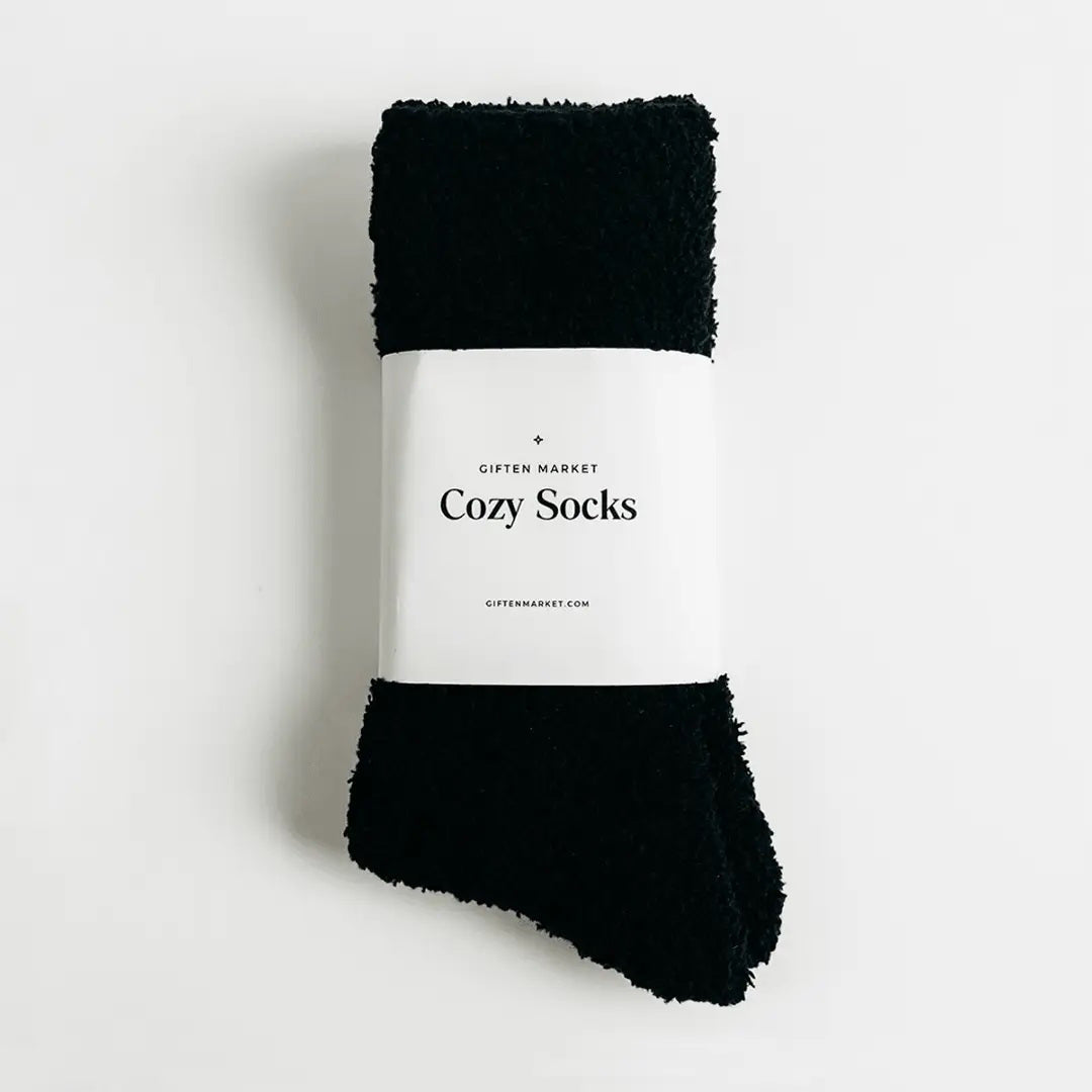 Beige fuzzy socks made from soft plush material are wrapped in a white &quot;Cozy Cloud Socks&quot; label displaying &quot;Giften Market&quot; and &quot;GIFTENMARKET.COM.&quot; These women&#39;s socks are neatly folded and viewed from above on a plain background.