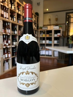 A 2019 bottle of DROUHIN HOSPICE DE BELLEVILLE MORGON BEAUJOLAIS from WINE: GRAPEVINE, made with Gamay grapes. The cream label with gold accents reads "Hospices de Belleville Morgon." Ideal for Burgundy wine lovers.