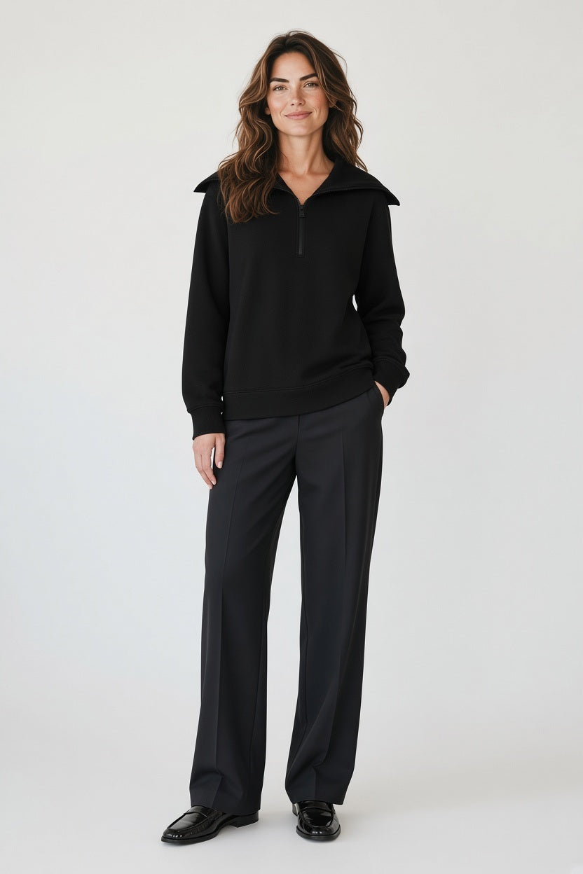 A person seen from behind, wearing a sleek, modern black SAVE THE DUCK - HINATA HALF ZIP TOP with a large collar and dark trousers.