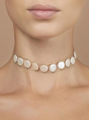 A close-up of a woman's neck wearing the GOLDISH Ladders to Bliss Pink Moonstone Choker, featuring two rows of round moonstones set in gold-toned chain links, by GOLDISH, against a neutral background.