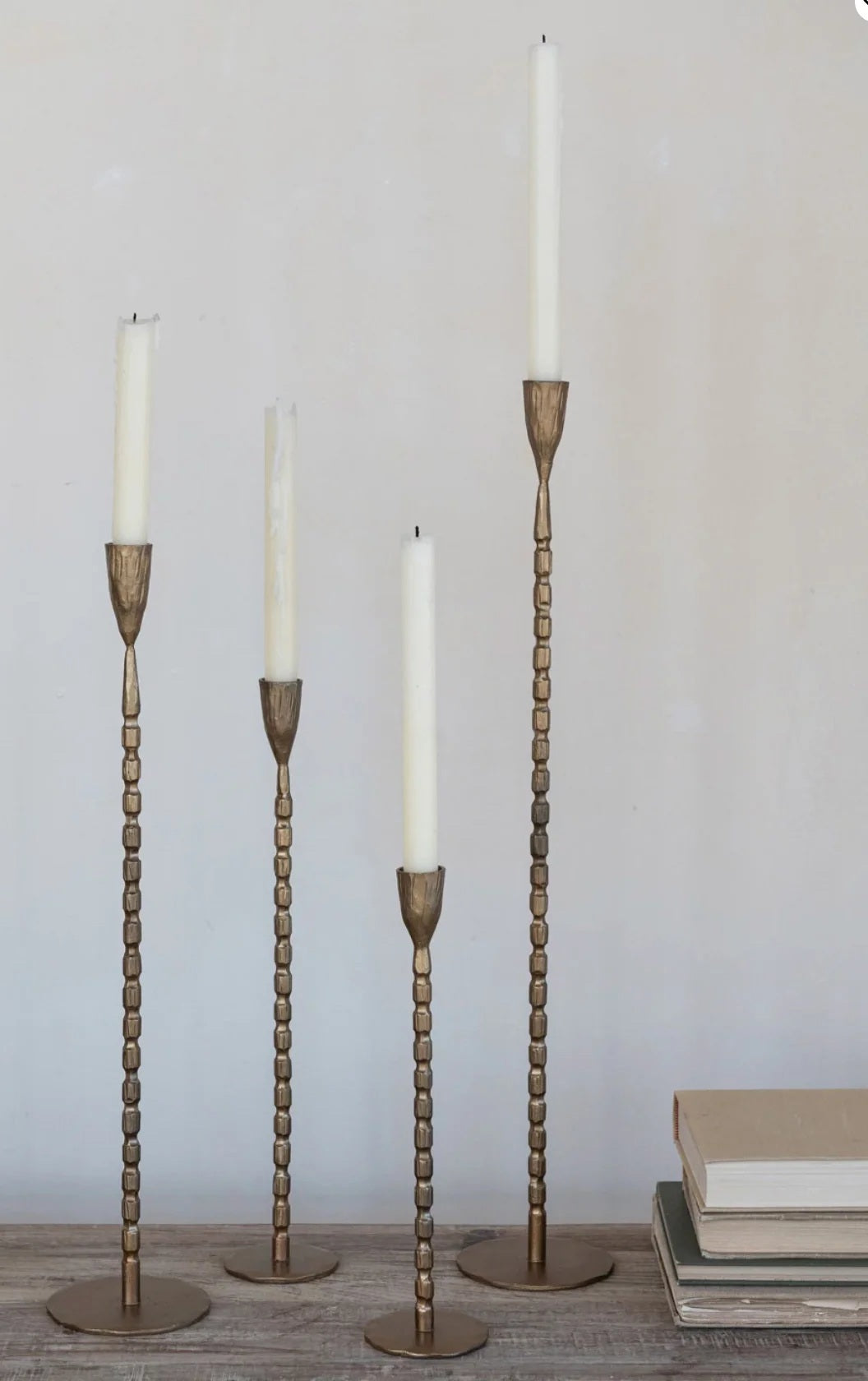 The CREATIVE COOP CAST IRON TAPER HOLDER IN BRASS FINISH, MEDIUM features a sleek, textured stem and round base, bringing elegant style to any setting.