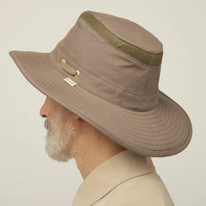 A man with a gray beard and mustache wears the TILLEY Airflo Hikers Hat T4MO-1 in olive, featuring UPF 50+ sun protection, and a beige button-up shirt, looking directly at the camera against a plain light background.