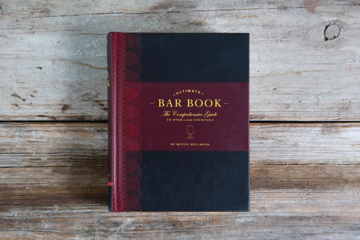 Cover of THE ULTIMATE BAR BOOK: THE COMPREHENSIVE GUIDE TO OVER 1,000 COCKTAILS BY MITTIE HELLMICH from CHRONICLE BOOKS, featuring a brown and olive green design with a wine glass icon—ideal for fans of classic cocktails.