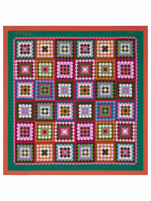 A vibrant quilt showcases geometric squares in pink, red, green, brown, white, and black with green and red borders—each echoing the bold design of the FRANCO FERRARI - CIALDA REVERSIBLE SILK SCARF by FRANCO FERRARI.