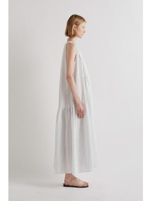 A person stands against a plain white background, wearing the MEIMEIJ Sleeveless Maxi Dress with Stripes, an ankle-length summer piece styled with flat sandals and a statement necklace for an effortlessly chic look.