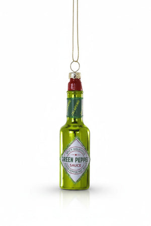 The CODY FOSTER GREEN PEPPER HOT SAUCE ORNAMENT is a shiny green glass decoration shaped like a hot sauce bottle, labeled "Green Pepper Sauce" with a gold hanging loop—ideal for collectors or as a unique gift.