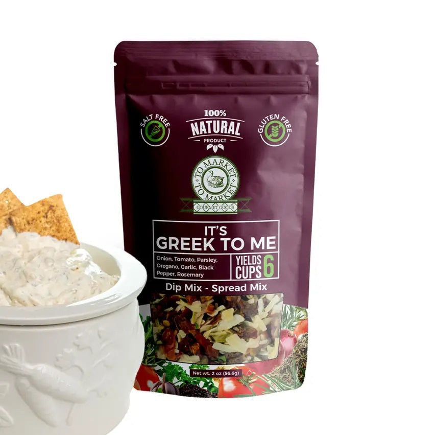 A purple bag of TO MARKET - IT’S GREEK TO ME DIP MIX by TO MARKET- DIPS &amp; SPREADS sits beside a bowl of white dip served with crackers. The packaging highlights a 6-cup yield and features key ingredients like onion, parsley, and oregano, making it an ideal foundation for a Mediterranean spread—just add feta cheese and kalamata olives for an authentic flair.